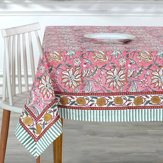 Floral patterned tablecloth on a wooden table with a white chair.