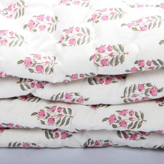 Stack of white fabric with pink floral patterns on a light gray background