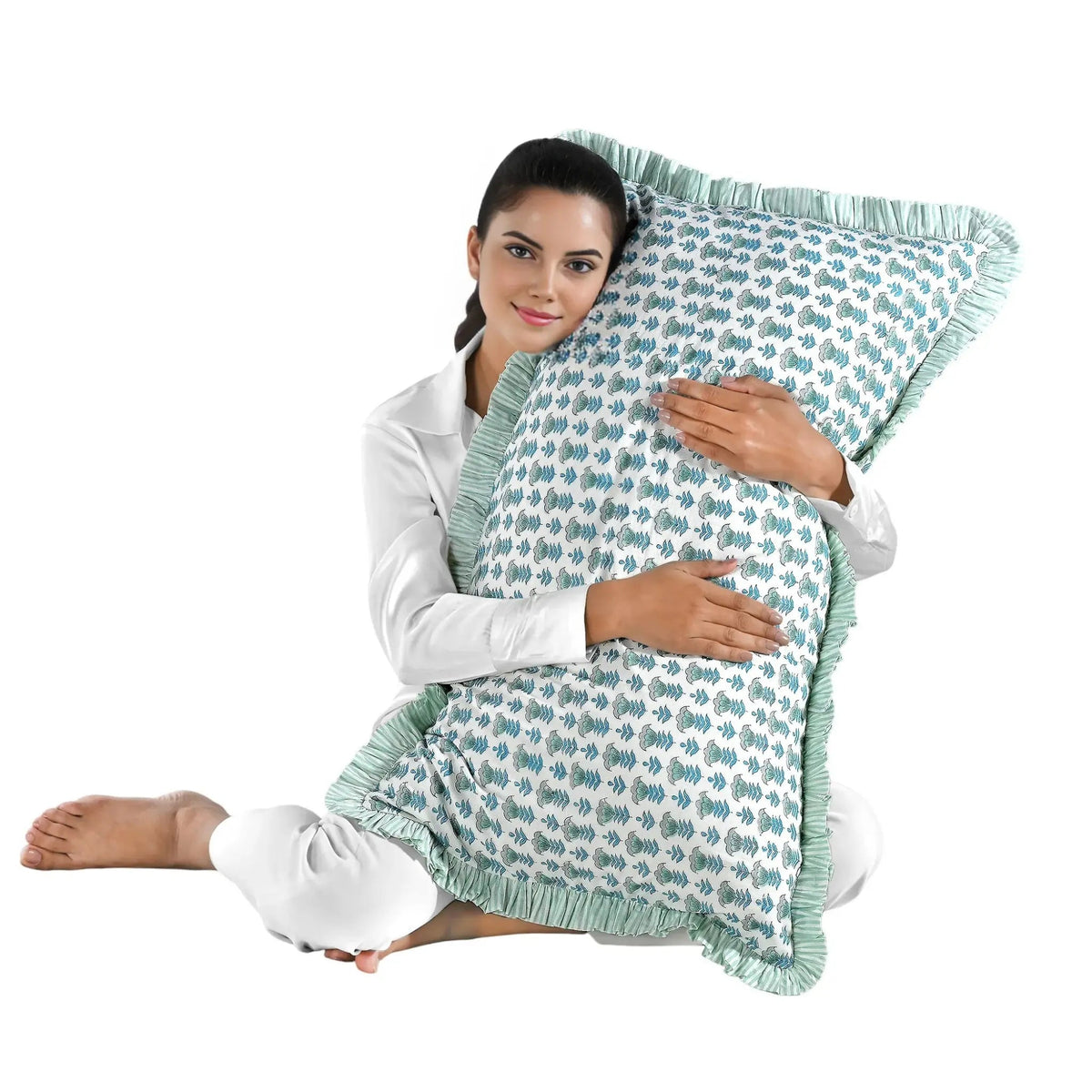 Woman holding a large blue floral block print cotton pillow with green edges.