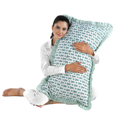 Woman holding a large blue floral block print cotton pillow with green edges.