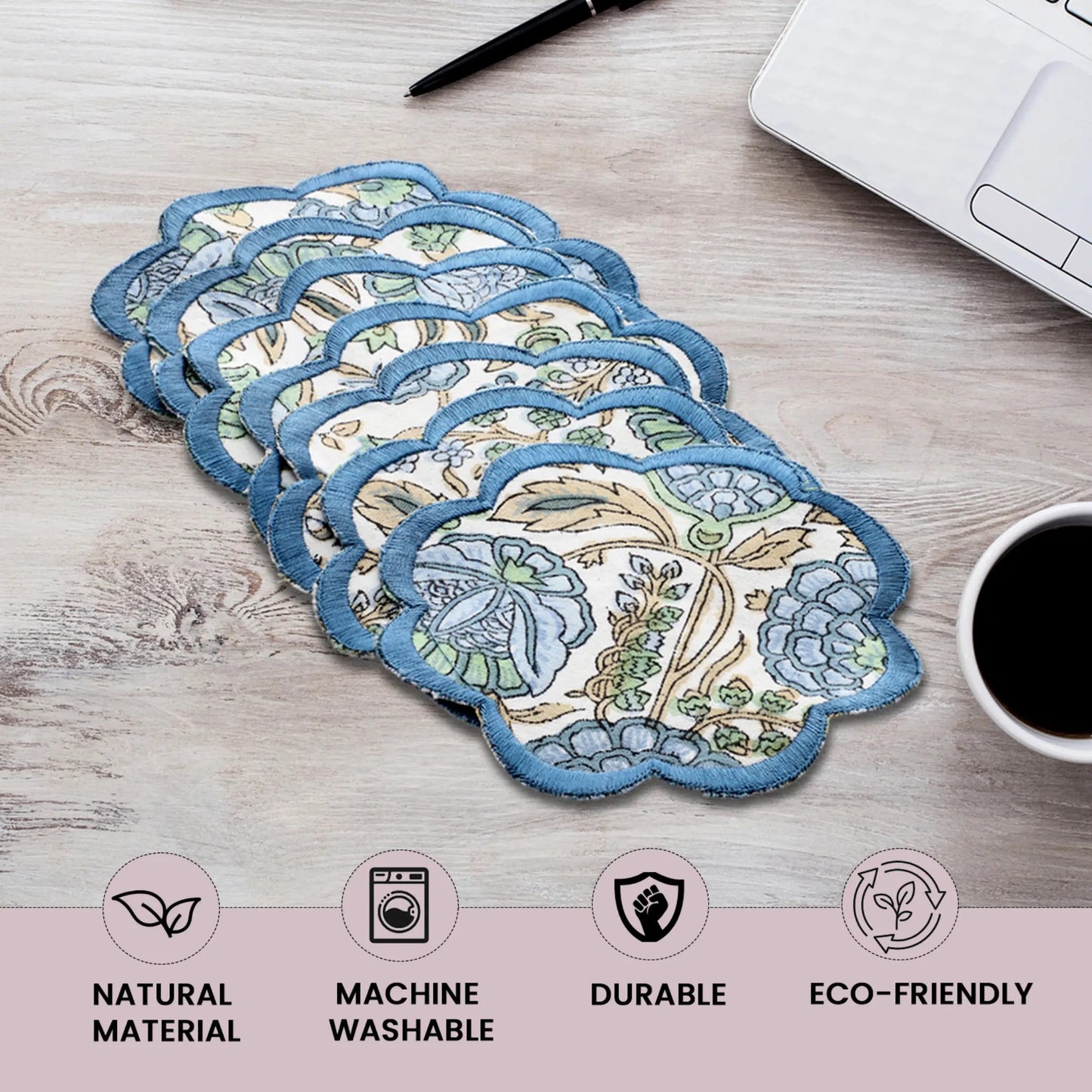 Set of floral coasters on a wooden surface with coffee and laptop.