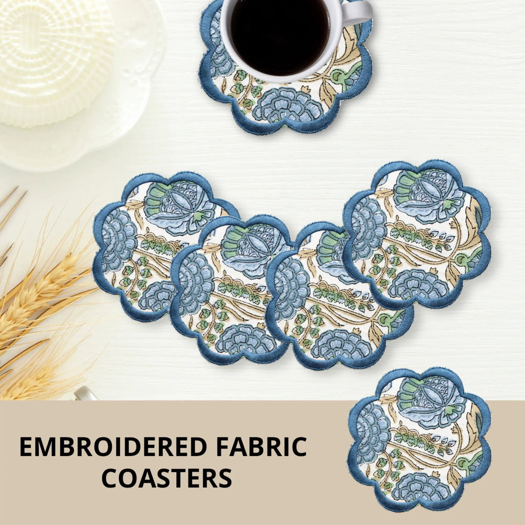 Set of embroidered fabric coasters with a cup of coffee on a white surface.