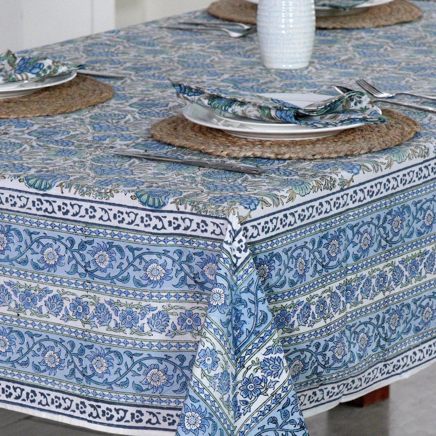 Table setting with a blue patterned tablecloth on a wooden table.