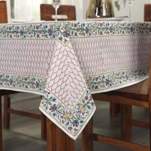 Dining table with a floral-patterned tablecloth and a vase of flowers.
