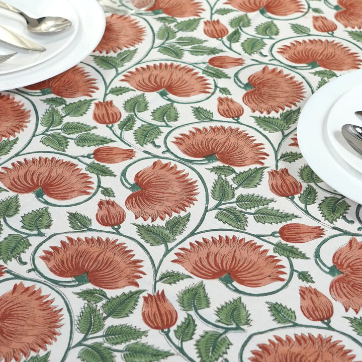 Floral patterned tablecloth with red flowers and green leaves on a white background