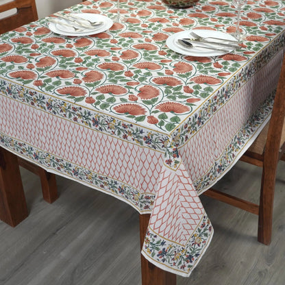 Dining table with a floral patterned tablecloth, plates, and cutlery.