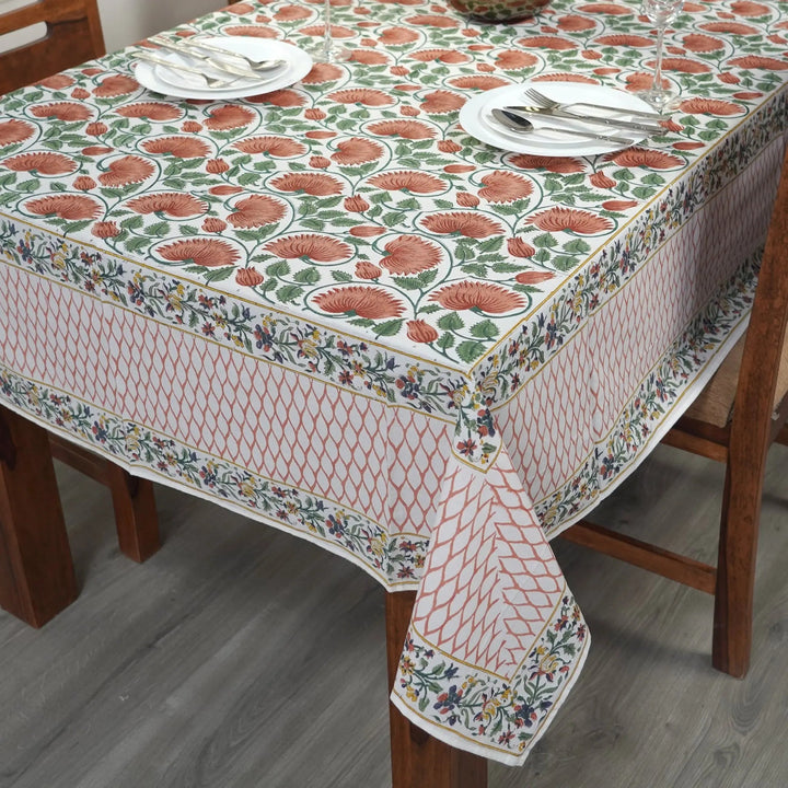 Dining table with a floral patterned tablecloth, plates, and cutlery.