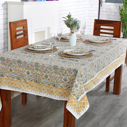 Dining table set with a floral tablecloth, plates, and glasses in a kitchen.