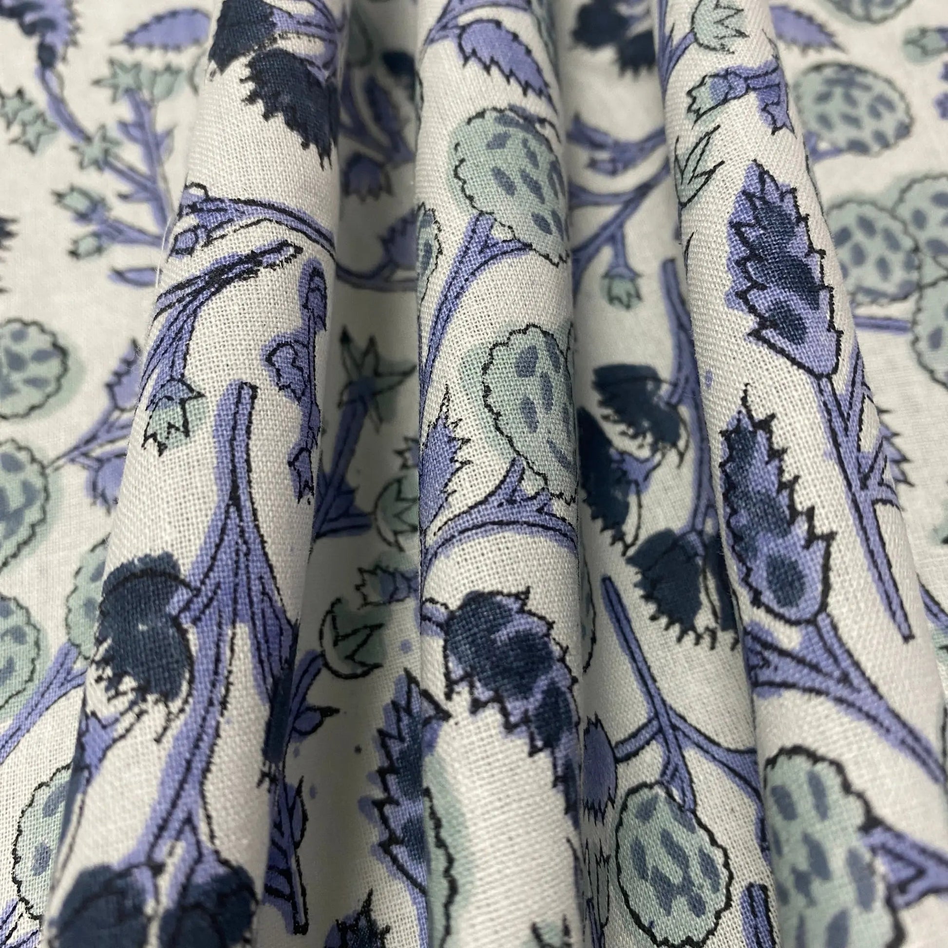 Stack of fabric with blue and green floral pattern on white background