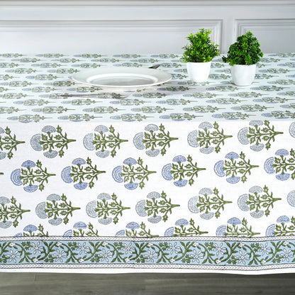 Decorative tablecloth with green and blue patterns on a table set with plates and plants.
