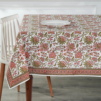 Floral patterned tablecloth on a wooden table with a white chair.
