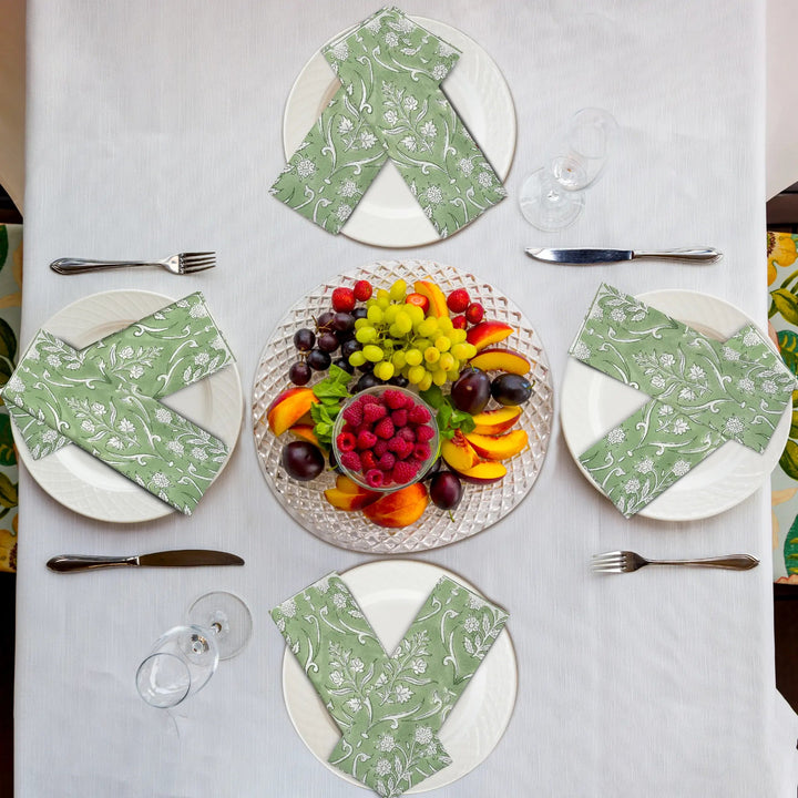 Table setting with plates, napkins, and a fruit platter on a white tablecloth.