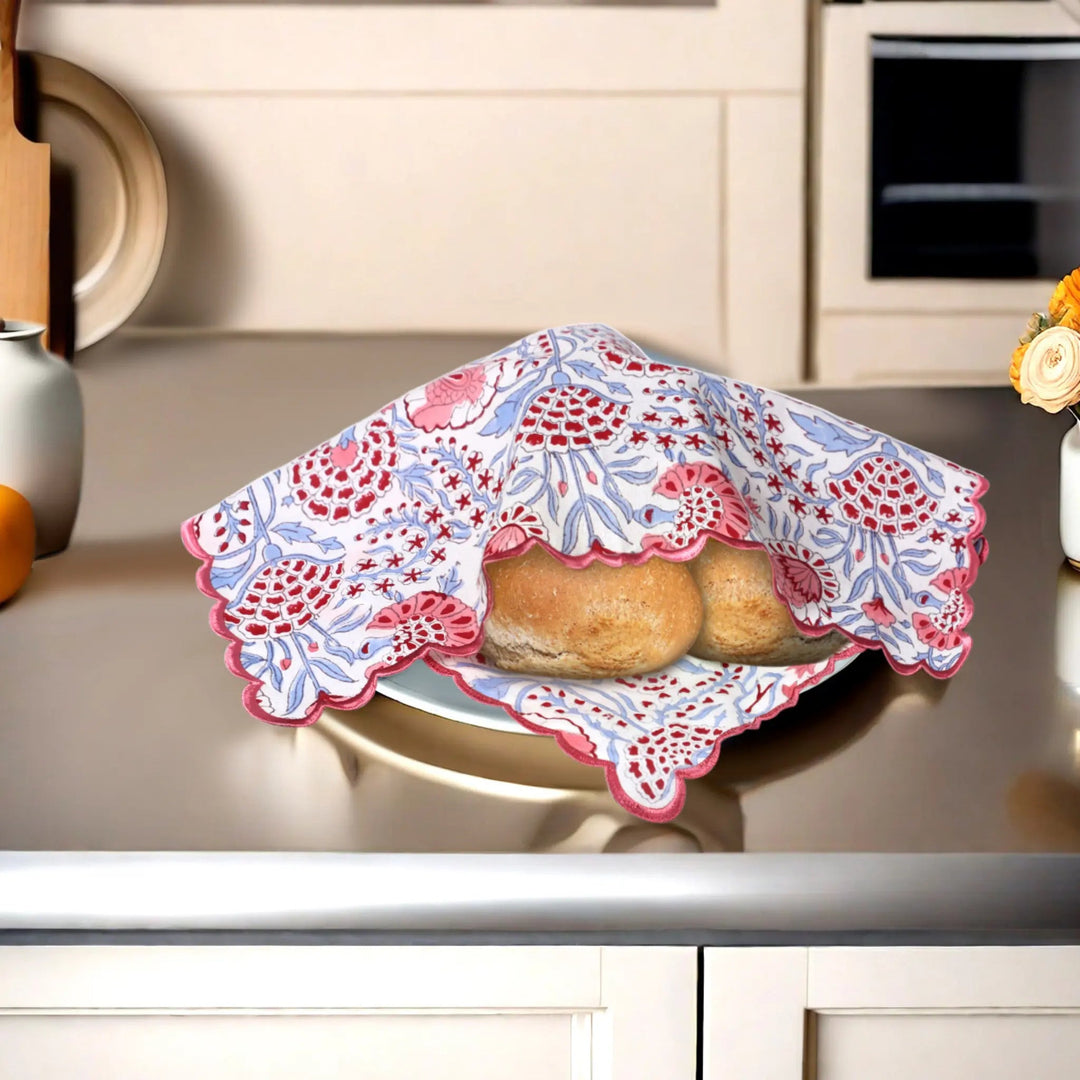 Baked goods in a decorative pink and blue cloth on a kitchen counter.