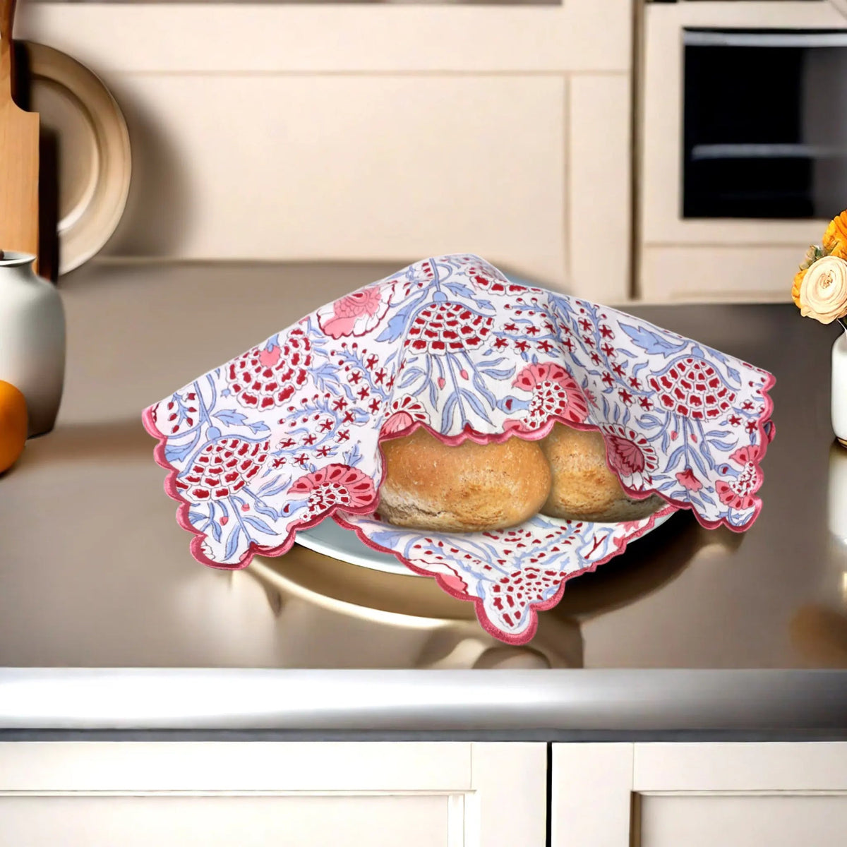 Baked goods in a decorative pink and blue cloth on a kitchen counter.
