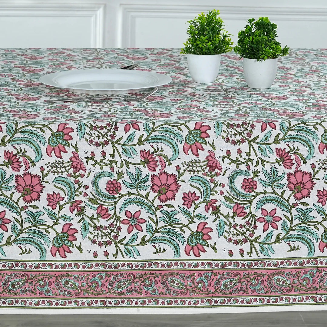 Floral patterned tablecloth on a table with two potted plants.