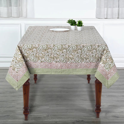 Tablecloth with paisley pattern on a wooden table in a room with white walls and gray floor.