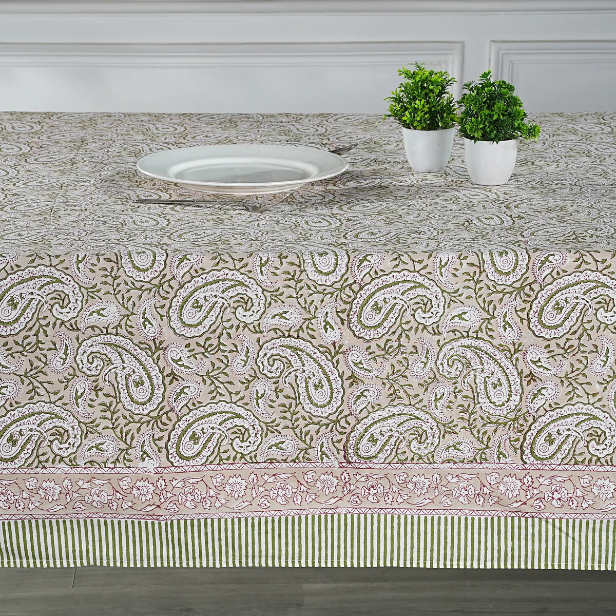 Tablecloth with paisley pattern on a dining table with plants and a plate.
