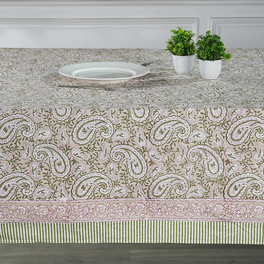 Tablecloth with paisley pattern on a dining table with plants and a plate.