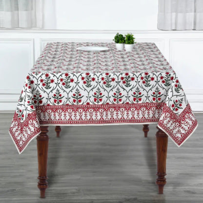 Tablecloth with floral pattern on a wooden table in a room with white curtains.