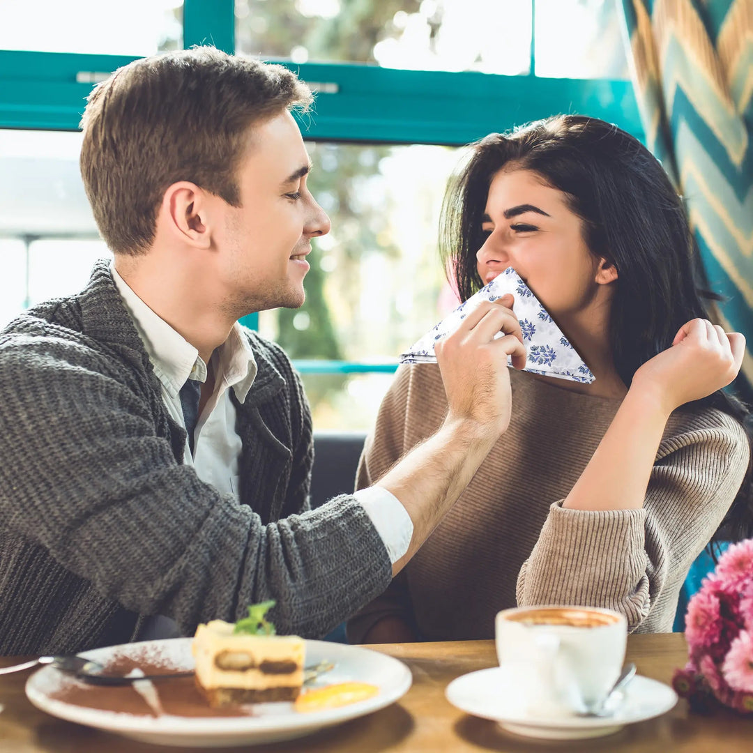 Man and woman sharing a moment at a cafe with a cup of coffee and cake.