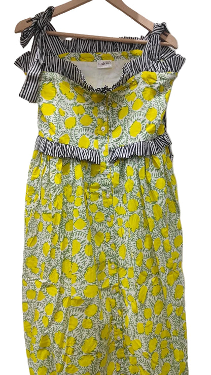 Yellow floral dress with black and white ruffled top on a hanger against a white background