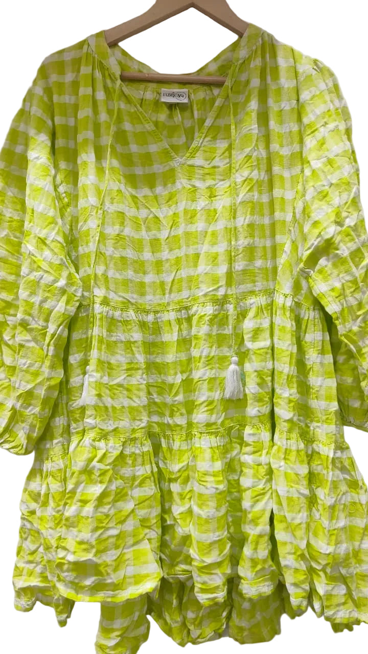 Green and white checkered dress on a hanger against a white wall