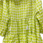 Green and white checkered dress on a hanger against a white wall