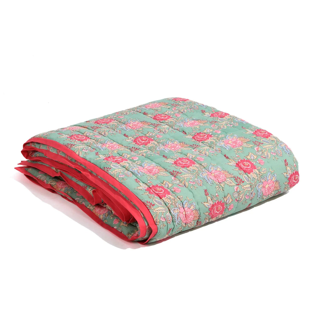 Floral quilt with red border on a white background