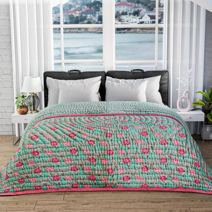 Bed with floral quilt in a room with large windows showing a waterfront view.