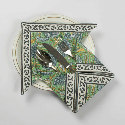 Decorative folded napkin with a pattern on a white plate with cutlery