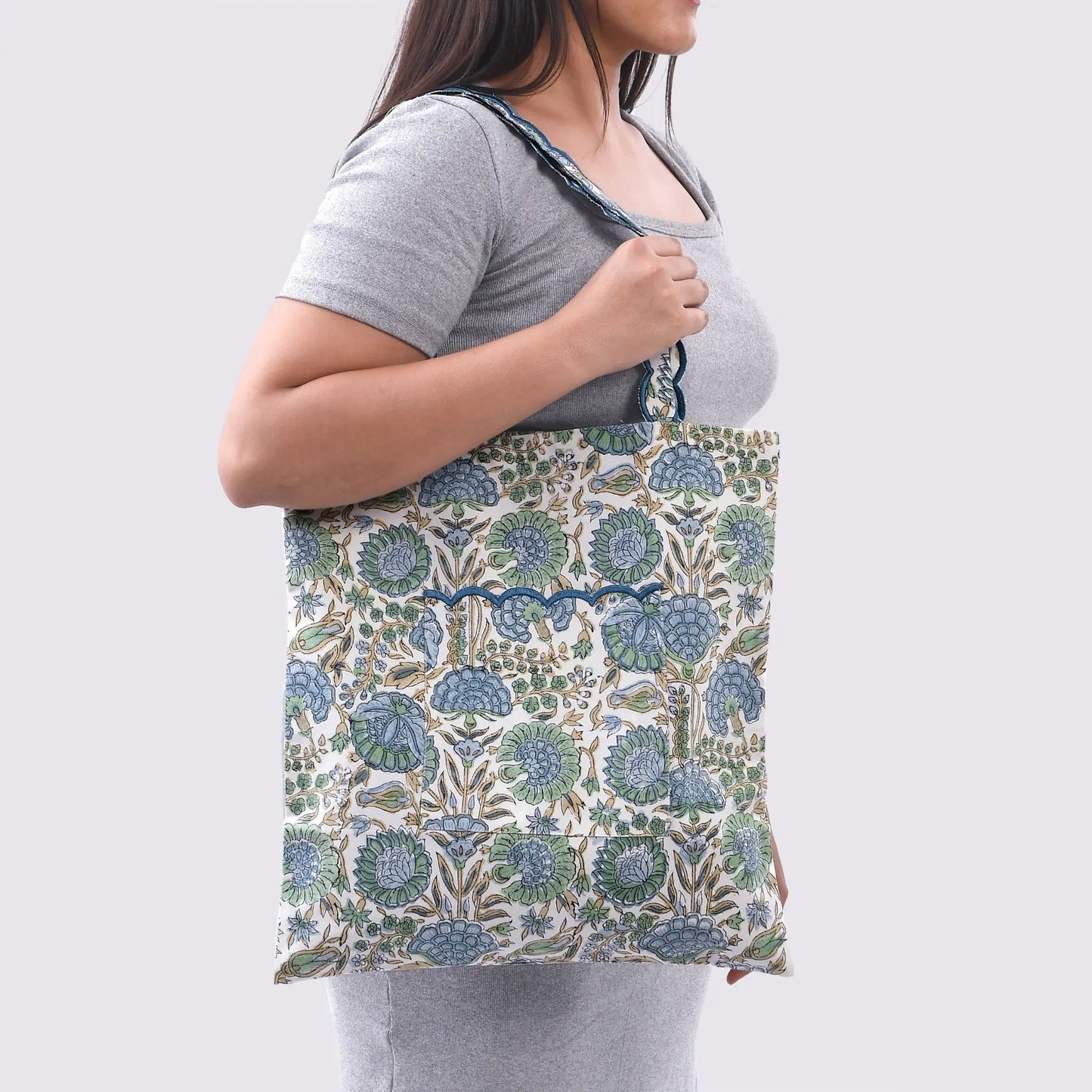 Person wearing a floral apron over a gray shirt on a white background