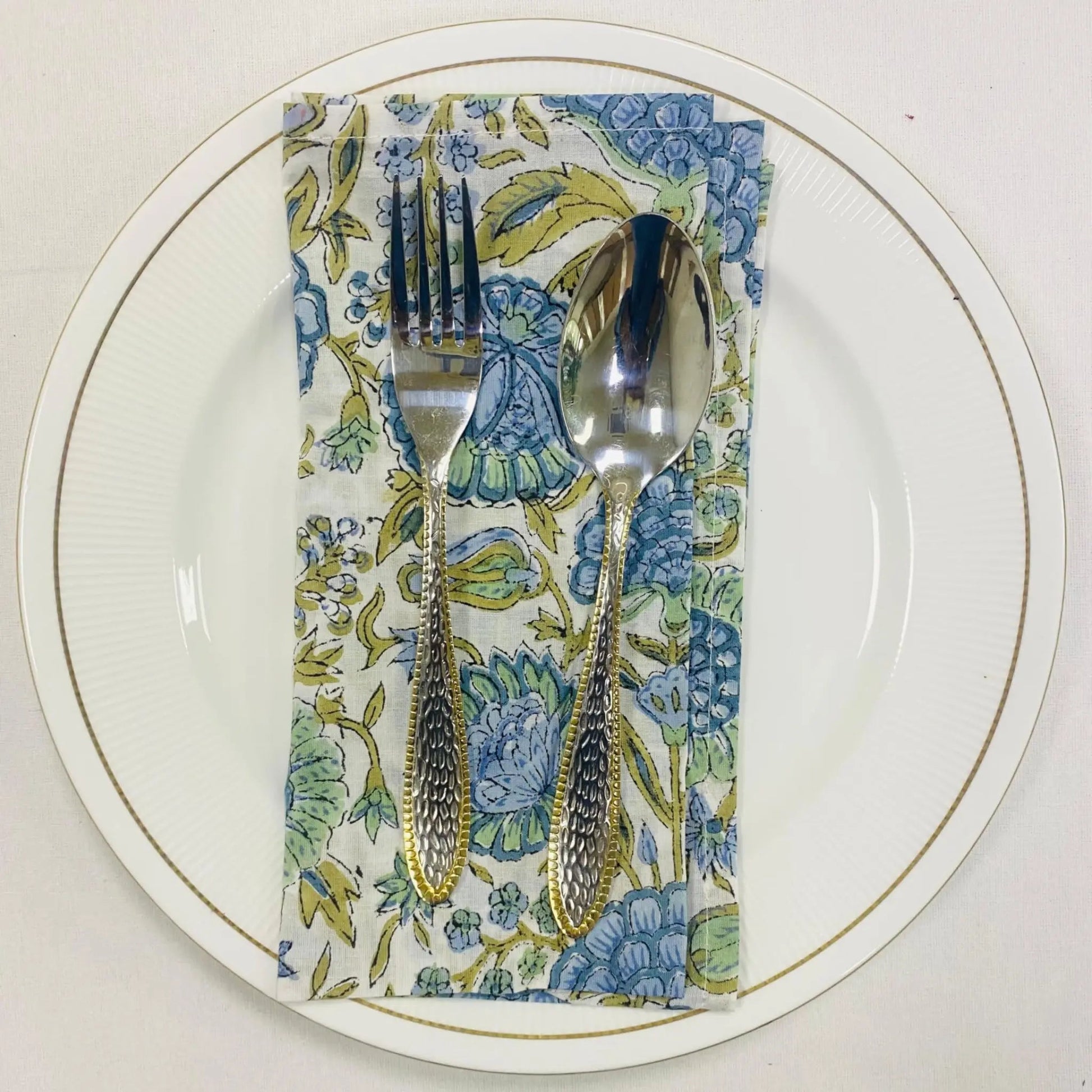 Silverware on a floral napkin with a white plate