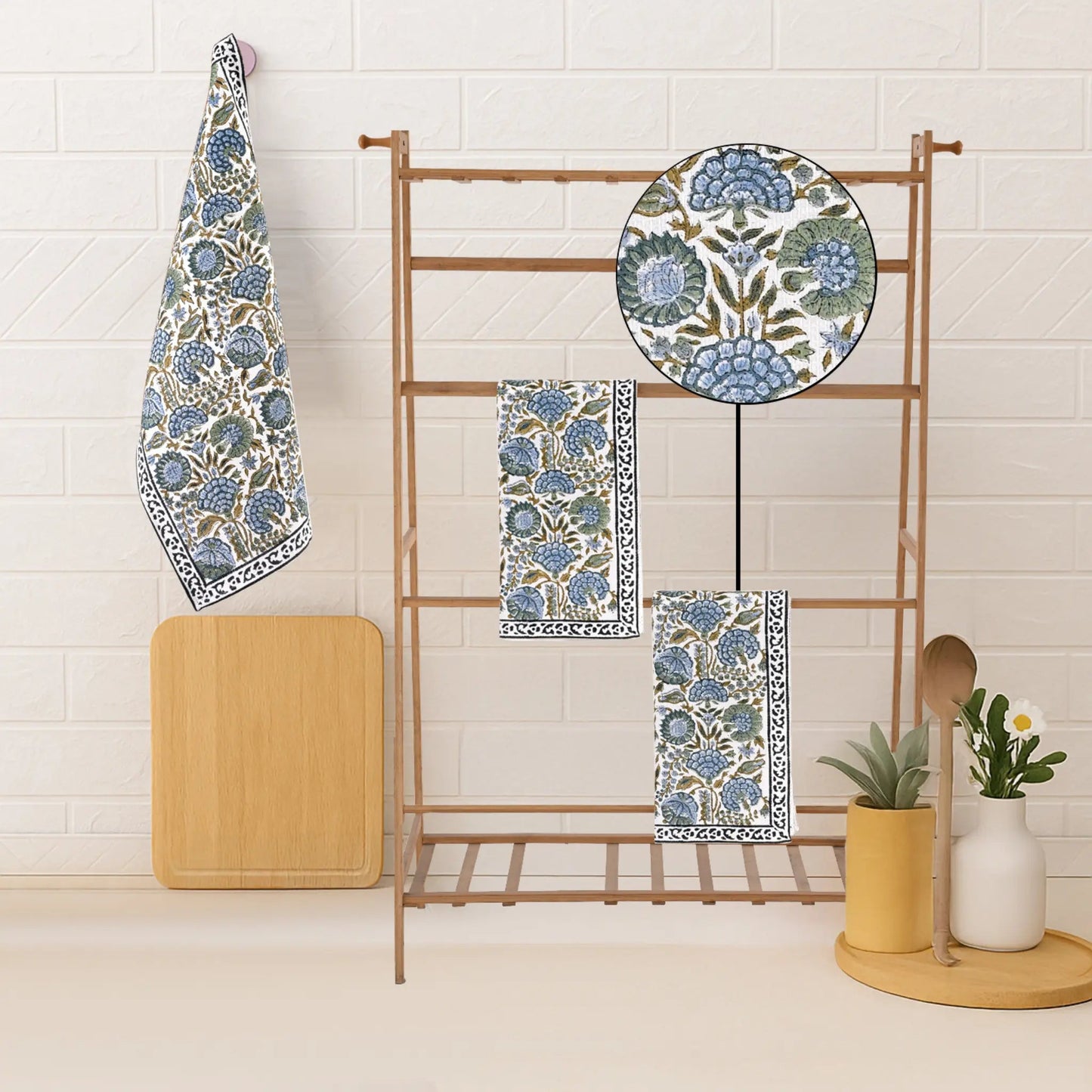 Set of blue and green patterned towels on a wooden rack against a white tiled wall.