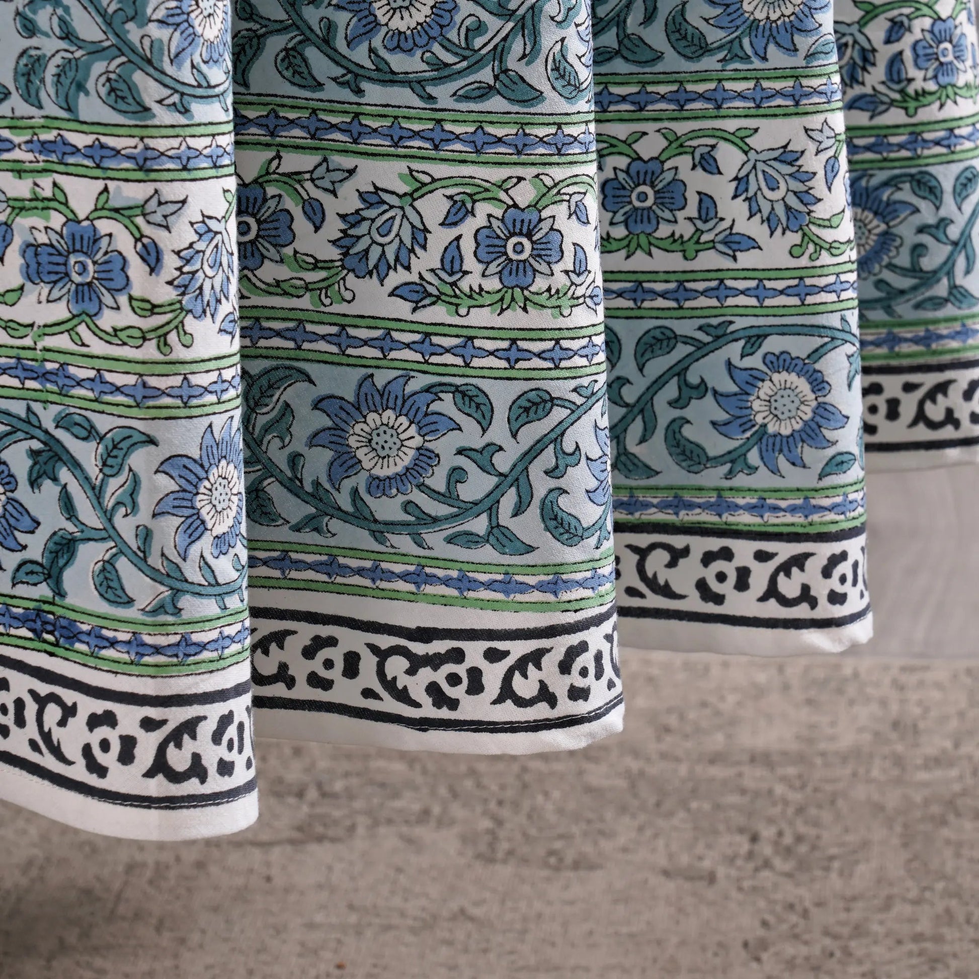 Close-up of patterned fabric with blue and green floral designs on a neutral background