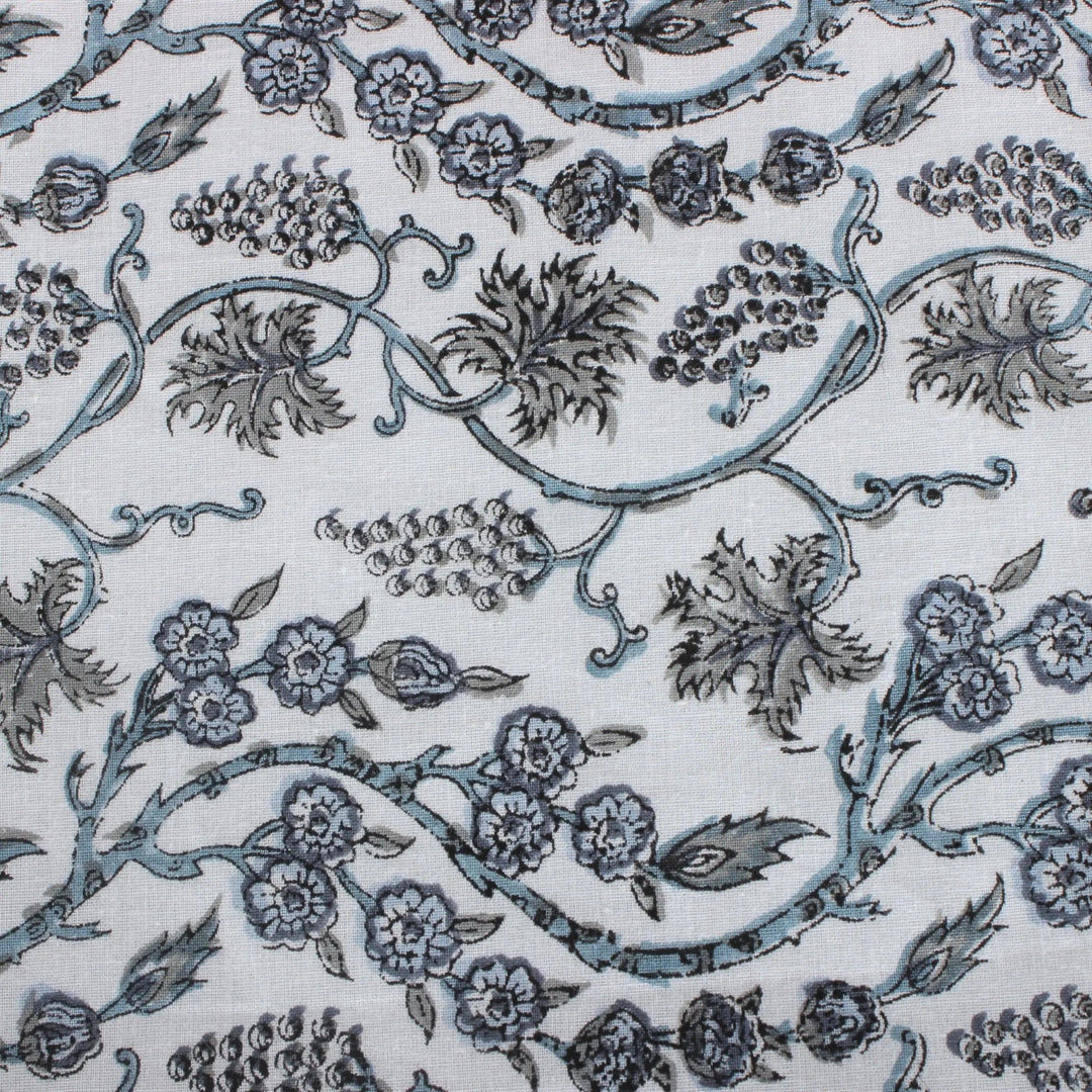 Patterned fabric with floral and vine designs in blue on a white background