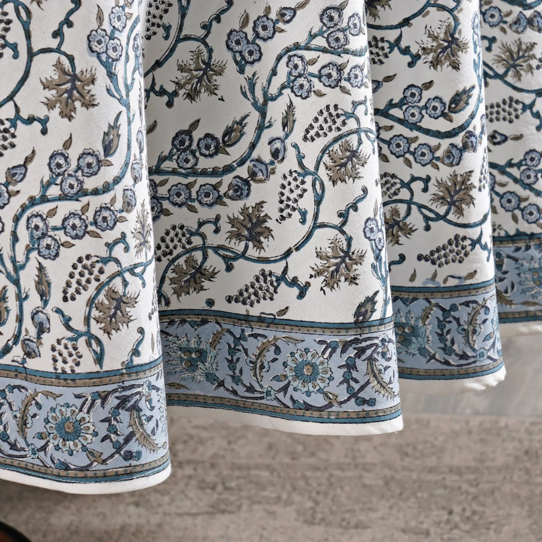 Close-up of patterned fabric with floral and vine designs on a neutral background