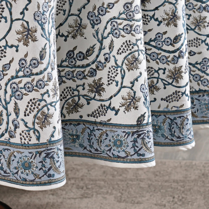 Close-up of patterned fabric with floral and vine designs on a neutral background