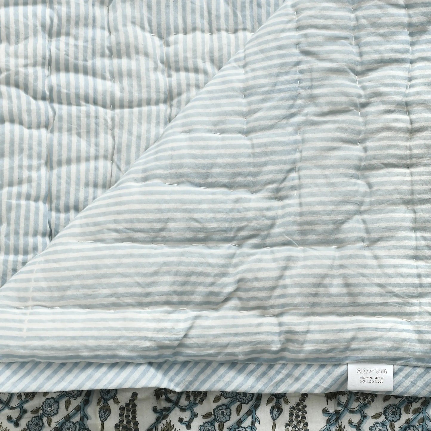 Quilted fabric with blue and white stripes on a floral background