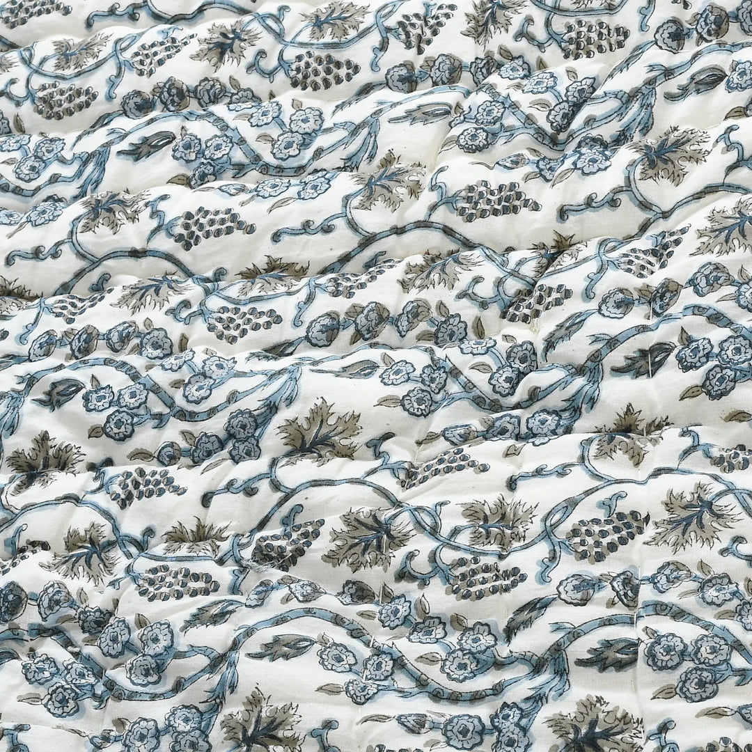 Floral and vine patterned fabric in blue and green on a white background