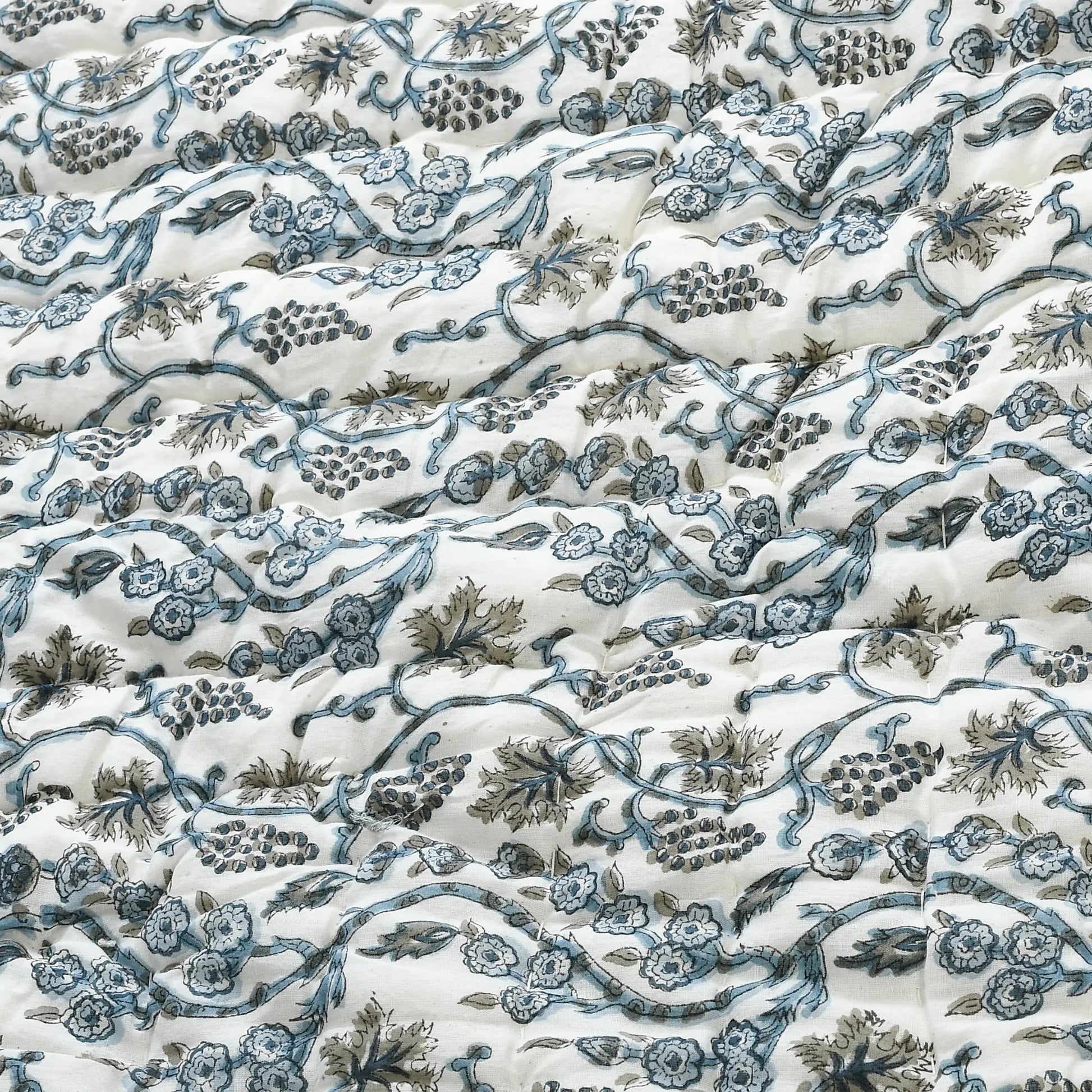 Floral and vine patterned fabric in blue and green on a white background