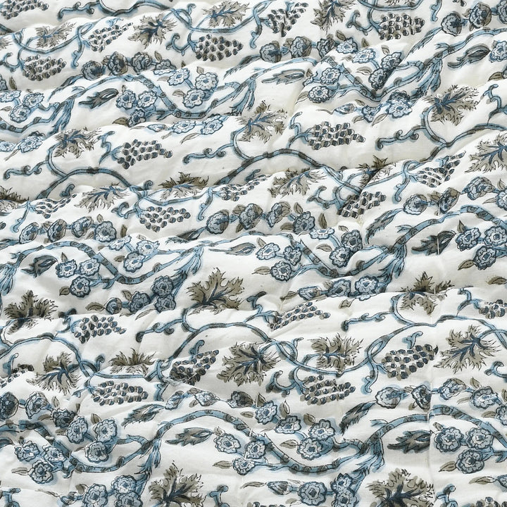 Floral and vine patterned fabric in blue and green on a white background