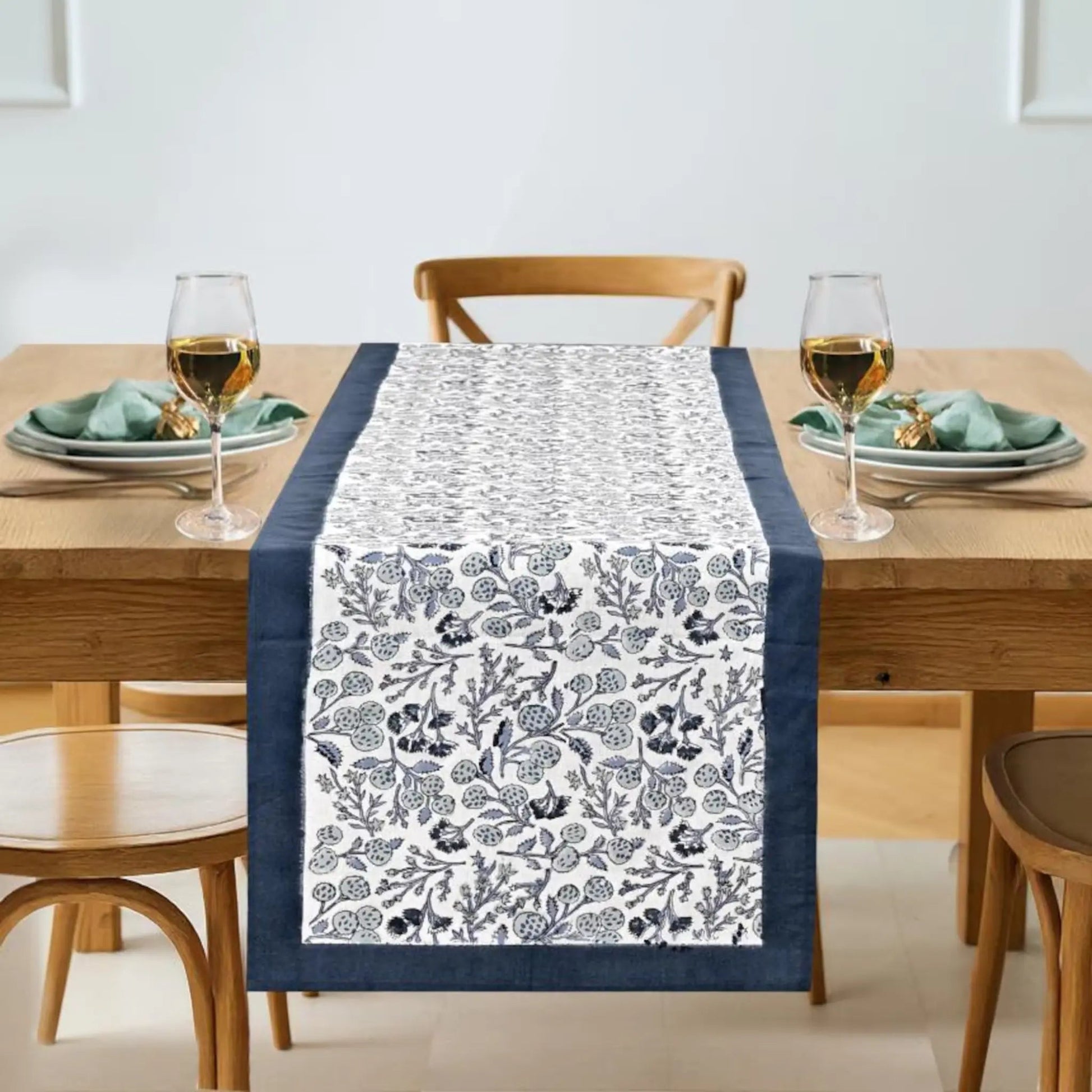 Table setting with a floral table runner on a wooden table.