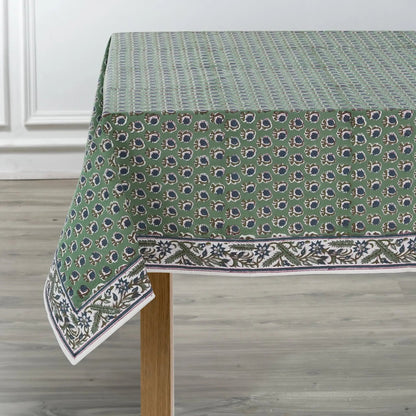 Green patterned tablecloth on a wooden table with a white wall background