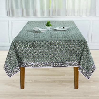 Tablecloth with a pattern on a wooden table in a room with white curtains.
