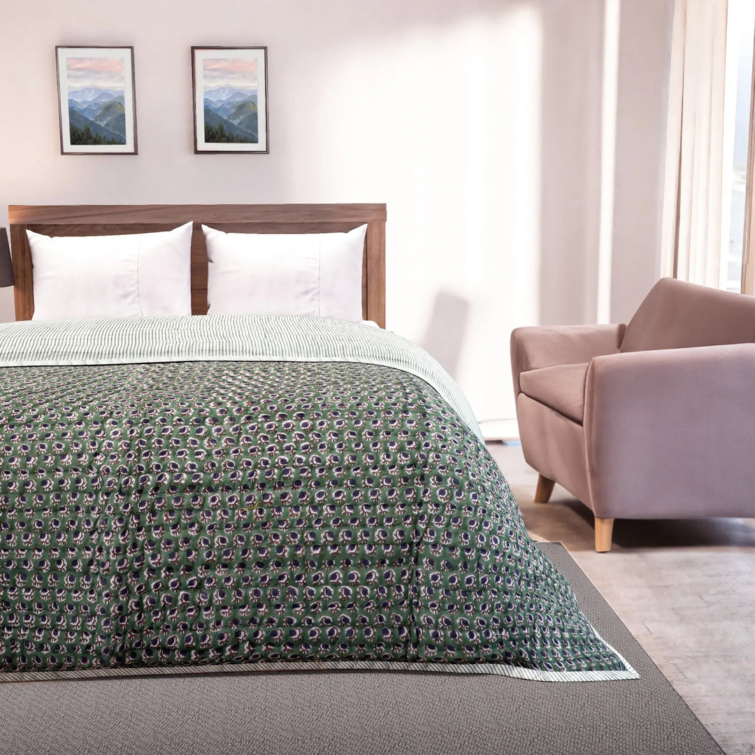 Bedroom with a bed covered in a green patterned comforter, a wooden headboard, and a pink armchair.