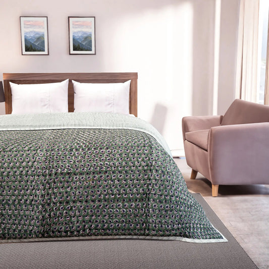 Bedroom with a bed covered in a green patterned comforter, a wooden headboard, and a pink armchair.