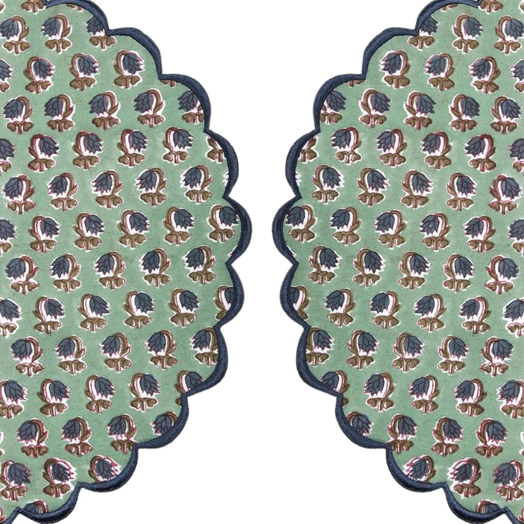Two green patterned coasters with scalloped edges on a white background