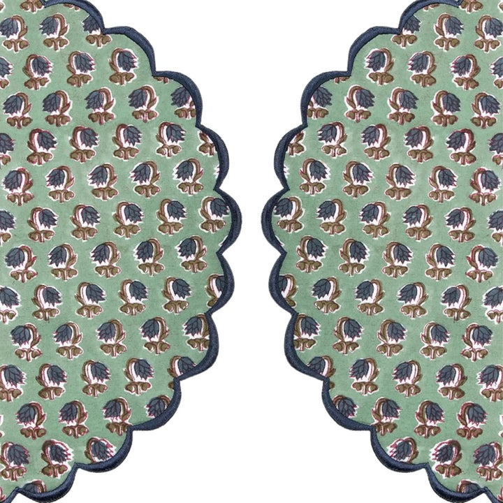 Two green patterned coasters with scalloped edges on a white background