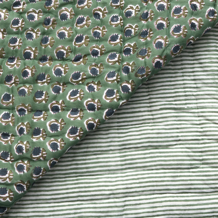 Close-up of green patterned fabric with a striped fabric underneath
