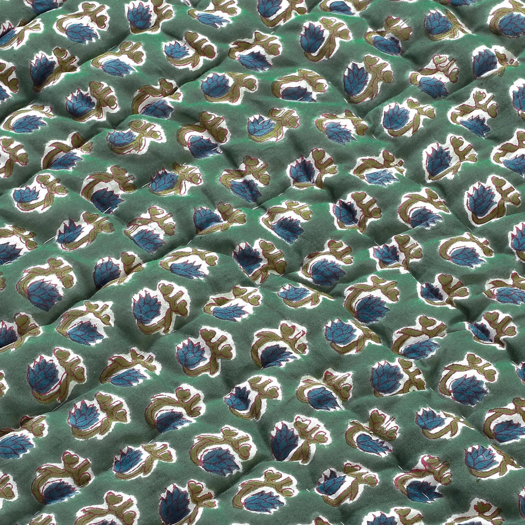 Close-up of a patterned fabric with blue and gold designs on a green background
